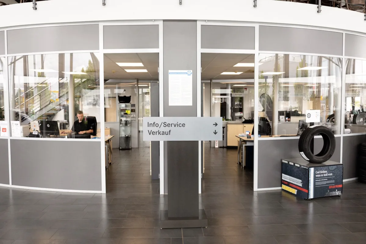 Wegweiser zu Info, Service und Verkauf, dahinter ein Beratungsplatz bei Conrady Automobile in Bitburg