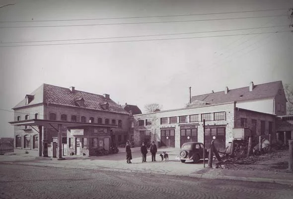 Historische Straßenansicht des Betriebs in der Trierer Straße in Bitburg mit einem Automobil vor dem Gebäude