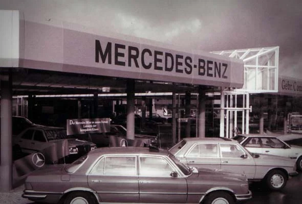 Verkaufshalle mit Mercedes-Benz Schriftzug, davor Mercedes-Benz Limousinen der Achtzigerjahre
