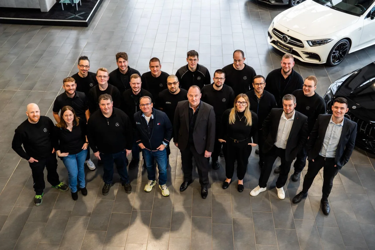 Das Team von Conrady Automobile in Bitburg, von der Empore aufgenommen, auf dem Fliesenboden des Showrooms